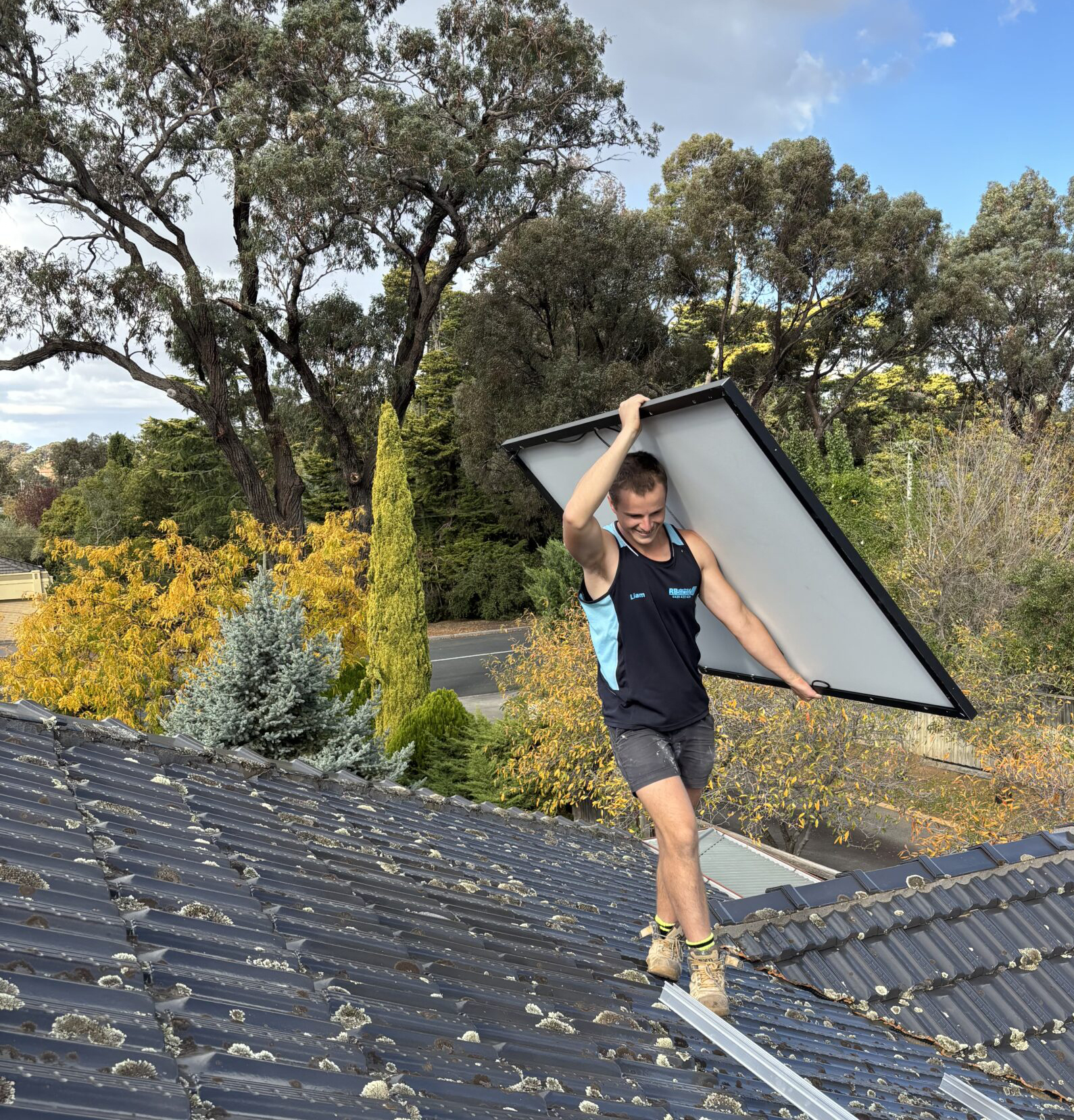 RB Solar & Electrical installer carrying a solar panel across a Bendigo roof