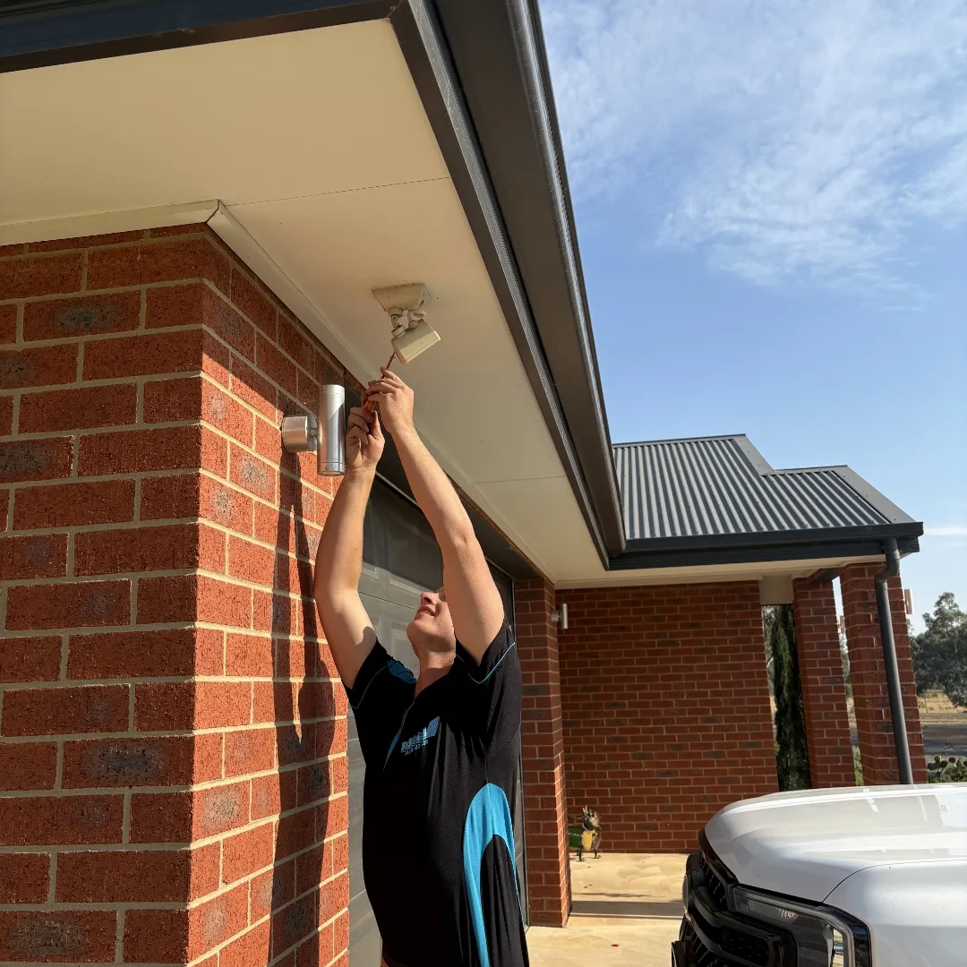 Technician installing a fitting under the eaves of a Bendigo home